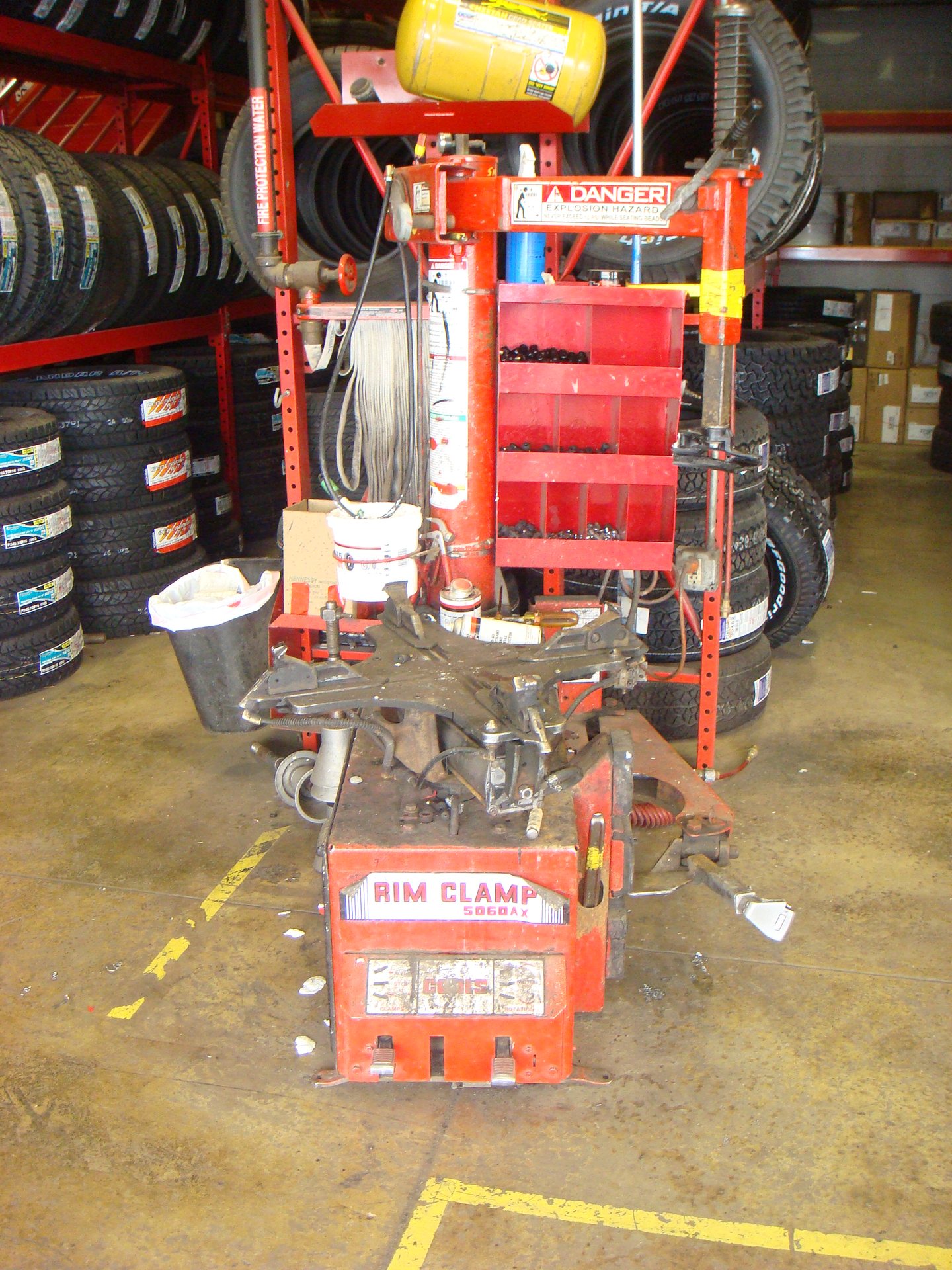 Coats 5060AX rim-clamp tire changer with yellow bead seater tank in a working independent shop